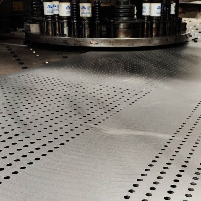 The CNC punching machine is punching holes on the steel sheet.