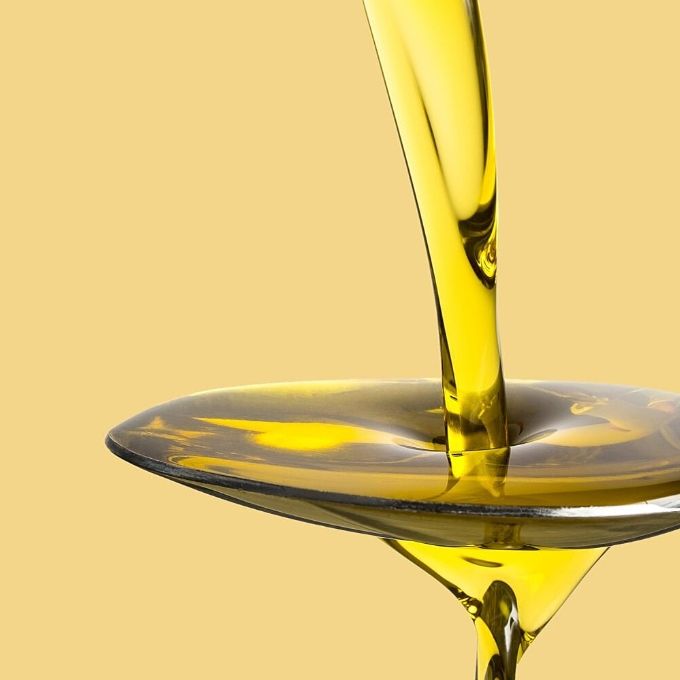 Edible oils are pouring into the spoon.