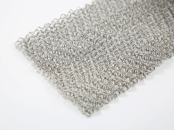A sheet of metallic Knitted mesh laid on a white background, showing its intricate, web-like structure.