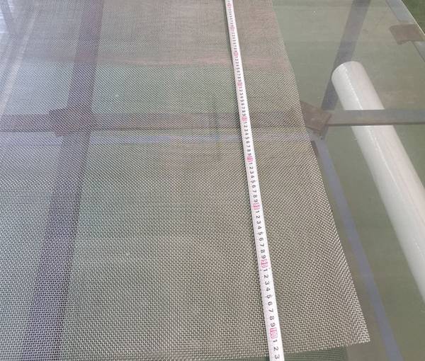Un tapeline est utilisé pour vérifier la largeur des mailles tissées en titane blanc.